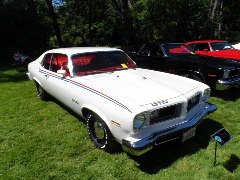 1971 Ford Ranchero - A white 1974 Pontiac GTO is displayed on a grassy lawn, with other vehicles visible in the background.