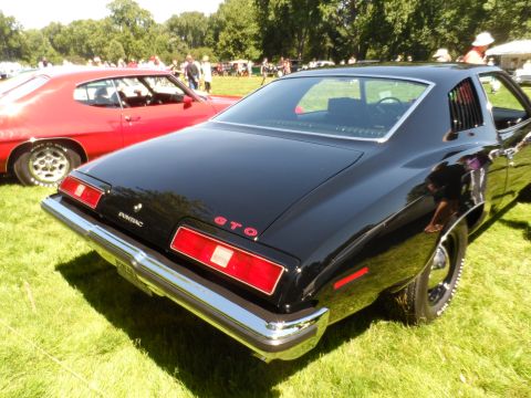 1971 Ford Ranchero - Rear view of a black 1970 Pontiac GTO parked on grass, with another red car visible behind it.