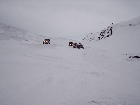 1996 Ford Bronco - Multiple SUVs navigate a challenging snowy terrain, highlighting their off-road capabilities in a winter environment.