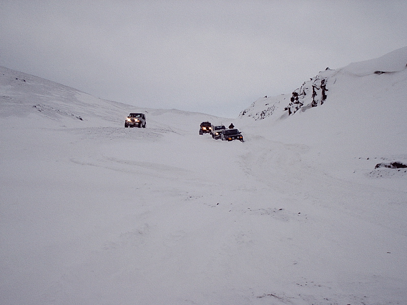 SUVs driving through a snowy mountain landscape under gray skies