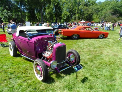 1971 Ford Ranchero - A purple hot rod convertible is parked on grass at an outdoor car show with other vehicles in the background.