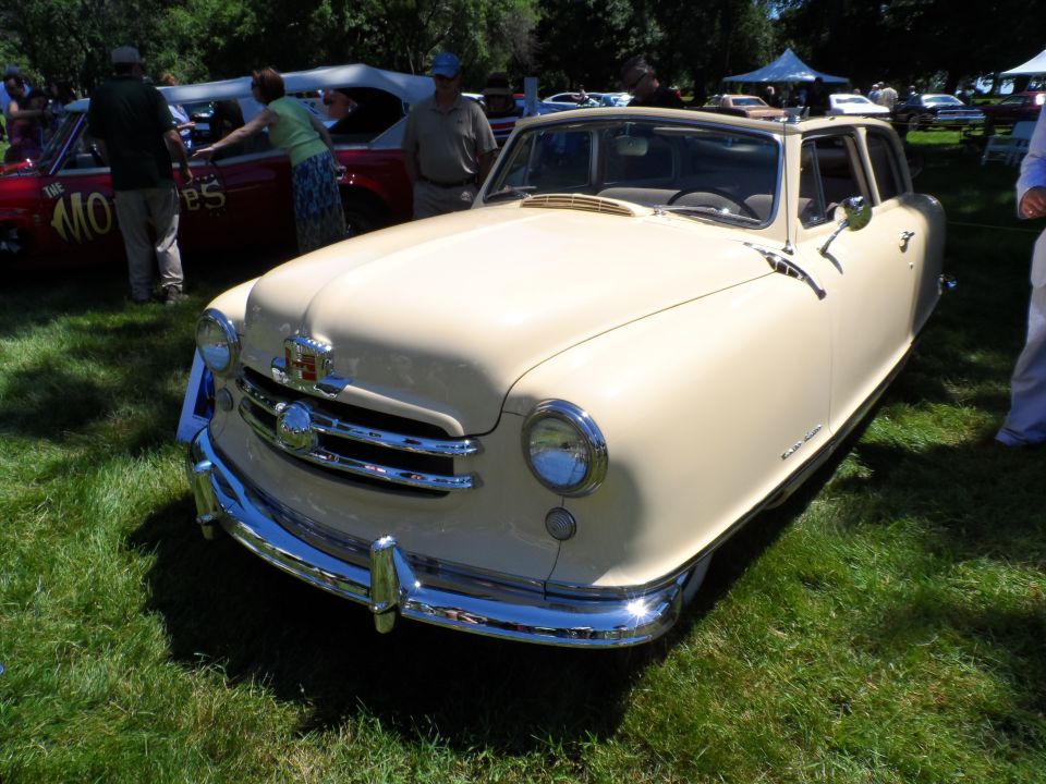 Beige car with chrome grille and bumpers, seen from a 3/4 front angle on grass