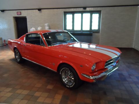 1971 Ford Ranchero - A classic red Ford Mustang coupe with racing stripes is parked indoors.
