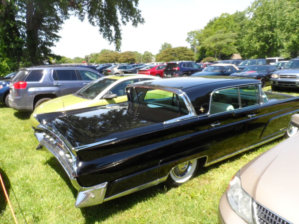 Black vintage Lincoln Continental parked on grass, other cars in background