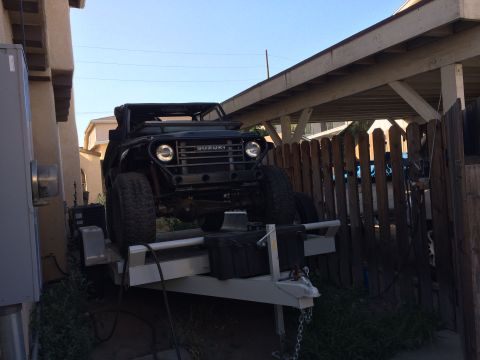 1968 Ford Mustang - A black Suzuki Samurai is parked on a trailer, viewed from the front. The Suzuki badge is clearly visible on the grille.