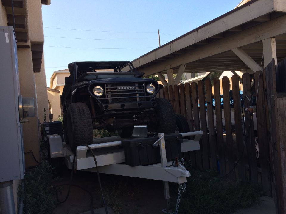Black Suzuki Samurai on trailer, front view. Suzuki badge visible