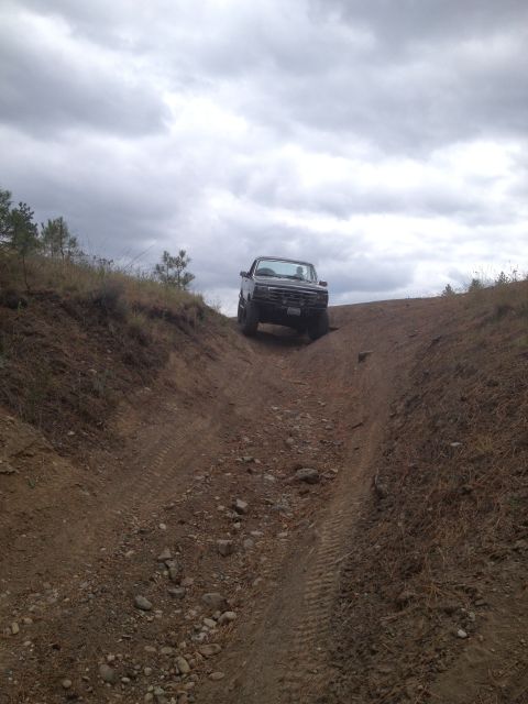 2005 Jeep Wrangler - A black pickup truck navigates a steep, rocky dirt path on an overcast day.
