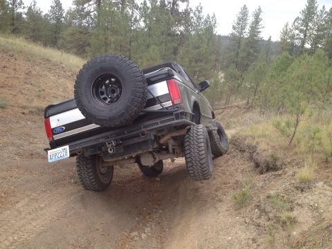 2005 Jeep Wrangler - This Ford Bronco is navigating a steep, dirt incline with its spare tire mounted on the back.