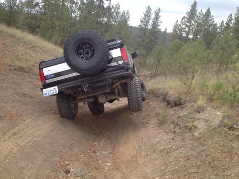 2005 Jeep Wrangler - Black Ford Bronco navigates a dirt trail with a spare tire mounted on the rear.