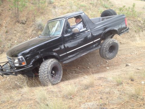 2005 Jeep Wrangler - Ford Bronco navigating a steep, dry dirt trail with one wheel off the ground.