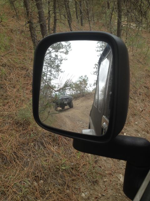 2005 Jeep Wrangler - An older SUV is seen in the side mirror of another vehicle driving on a dirt road through a wooded area.