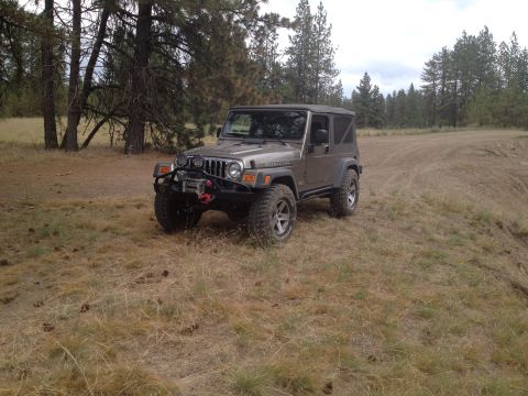 2005 Jeep Wrangler - A 2005 Jeep Wrangler Rubicon is parked on a dry, grassy hillside with trees in the background.