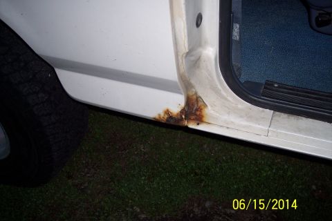 1990 Ford Bronco - Rust is forming on the lower part of the door sill of a white vehicle.