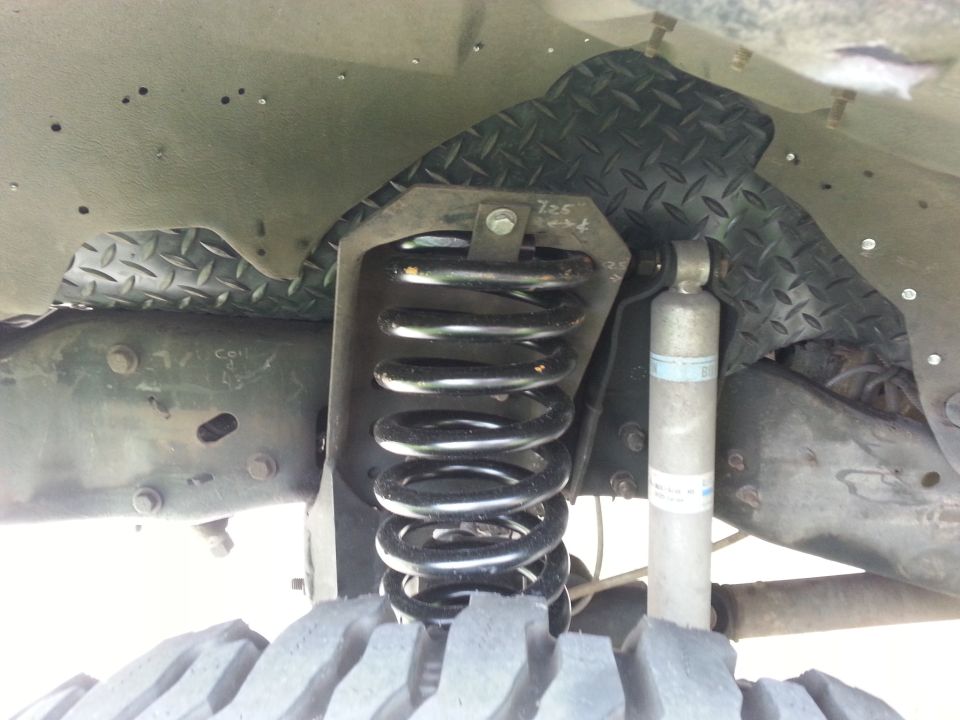 Close-up of front suspension coil spring and shock absorber with diamond plate liner