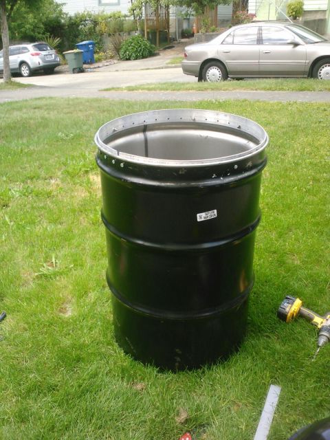 2008 Ford F-250 - A black metal barrel sits on a grassy lawn, with two cars and a trash can visible on the street behind it.