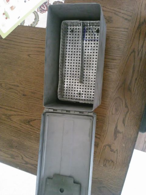 2008 Ford F-250 - A metal tray with a perforated surface is placed inside an open metal container, resting on a wooden surface.