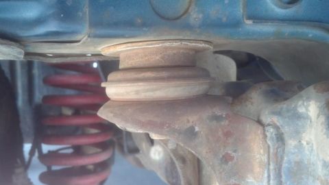 1995 Ford Bronco - A close-up view of a rusty suspension component and a red coil spring.