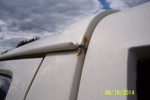 1990 Ford Bronco - Close-up of rust forming on the seam of a white SUV's roofline.