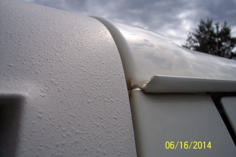 1990 Ford Bronco - Water droplets on a white vehicle body panel, with a seam and trim piece visible. Supermotors.net logo in corner.