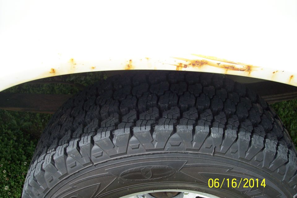 White vehicle fender with rust above a tire. Visible text: 06/16/2004 SUPERMOTORS.NET