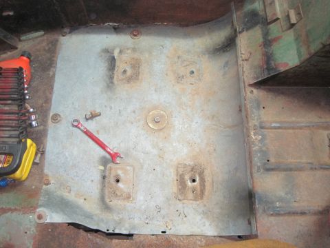 1946 Jeep CJ5 - Tools and a wrench lie on the metal floor pan of a vehicle, with mounting points visible.