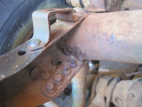 1946 Jeep Willys - Close-up view of heavily rusted vehicle frame and suspension components, with a tire visible on the left.