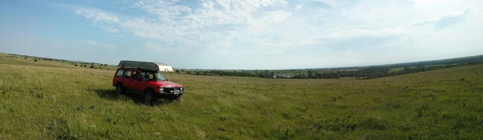Red SUV parked in grassy field, canoe on roof rack