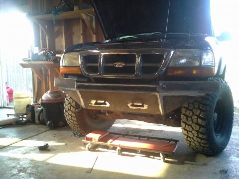 2000 Ford Ranger - A black Ford Ranger is parked in a garage with its hood up, a custom front bumper and off-road tires.