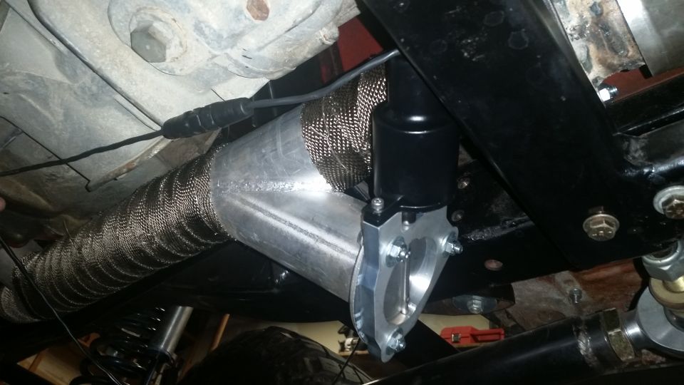 Close-up of vehicle exhaust pipe with heat wrap and a black valve attached