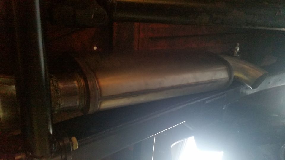 Exhaust muffler and bent pipe under a vehicle, with SuperMotors logo visible
