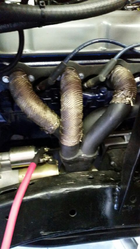 1968 Ford Bronco - Close-up view of an exhaust manifold wrapped in heat-resistant material, with spark plug wires visible.