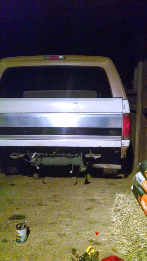 1995 Ford Bronco - The rear of a Ford Bronco is shown with its bumper removed, revealing wiring and suspension components.