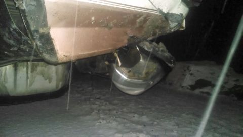 1995 Ford Bronco - The rear of a vehicle shows significant damage to the bumper and lower bodywork, resting in a snowy environment.