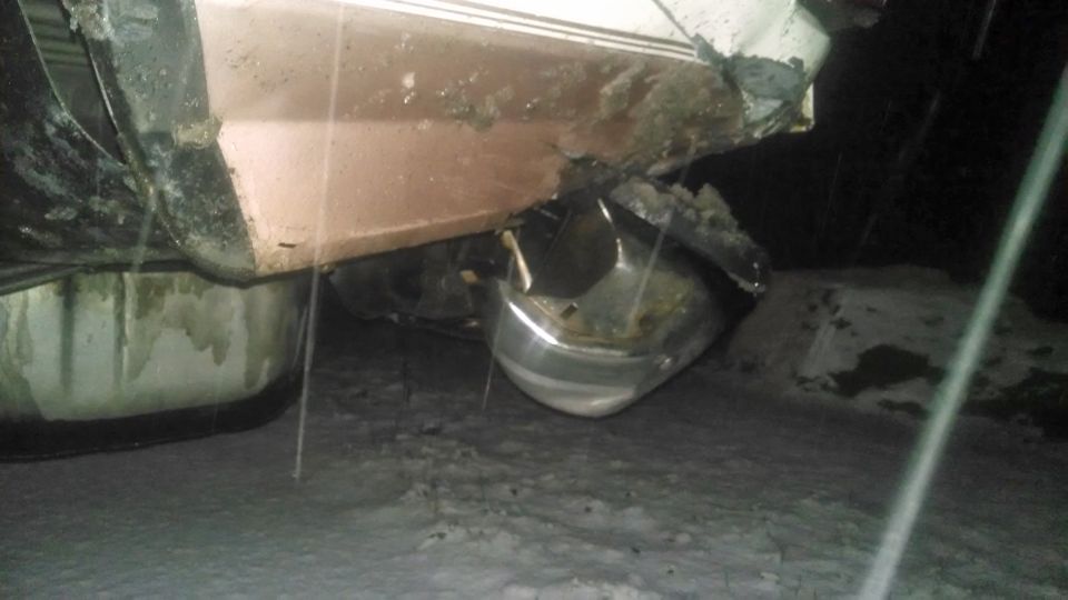 Damaged rear bumper and lower body panel of a vehicle, possibly a truck or SUV, in a snowy outdoor setting