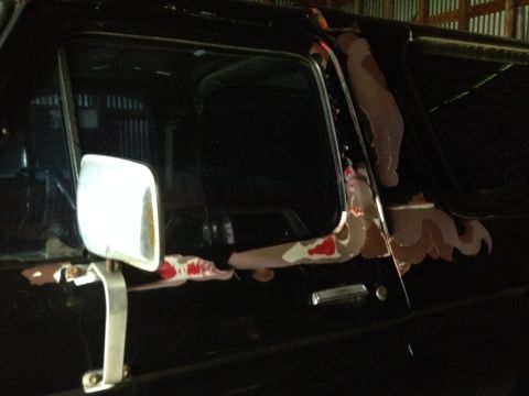 1978 Ford Bronco - The side of a black vehicle shows chipped paint and rust around the door frame and mirror mount.