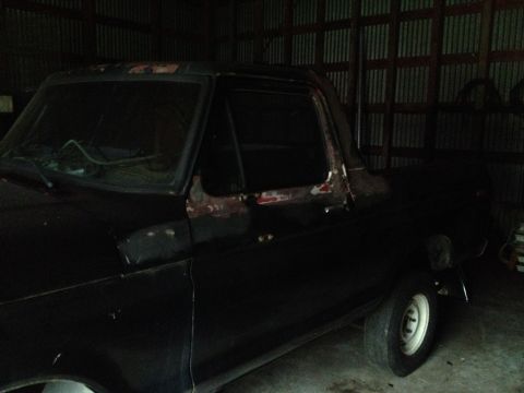 1978 Ford Bronco - This 1978 Ford Bronco is seen in a garage with visible rust on its side door.