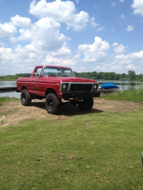 1978 Ford Bronco - A red 1979 Ford F-Series pickup truck sits on a grassy area next to a lake under a cloudy sky.
