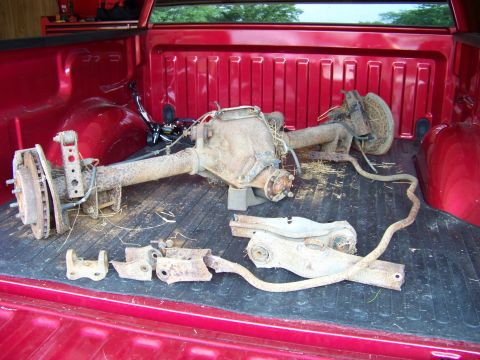1999 Mercury Grand Marquis - Rear axle assembly and suspension parts are shown in the bed of a red pickup truck.