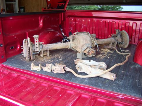 1999 Mercury Grand Marquis - A disassembled rear axle assembly is loaded into the bed of a red pickup truck.