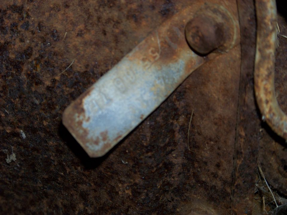 Close-up of a rusted metal bracket with faint stamped text and a bolt head