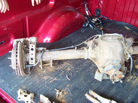 1999 Mercury Grand Marquis - A rear axle assembly, likely from a truck, is shown disassembled and placed in the bed of a red pickup truck.