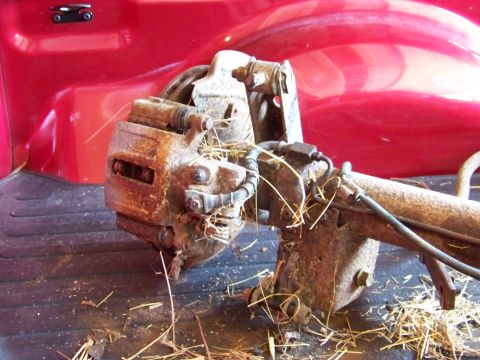 1999 Mercury Grand Marquis - A rusty brake caliper and axle assembly is shown in the bed of a red truck.