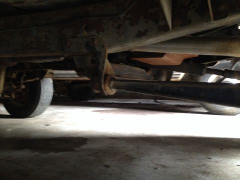 1978 Ford Bronco - The underside of a vehicle shows its suspension components and a tire, with visible rust.