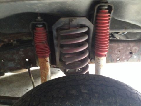1978 Ford Bronco - Close-up view of the rear suspension system, red shock absorbers and a coil spring.