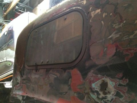 1978 Ford Bronco - Rusted vehicle body panel with a window, possibly undergoing restoration.