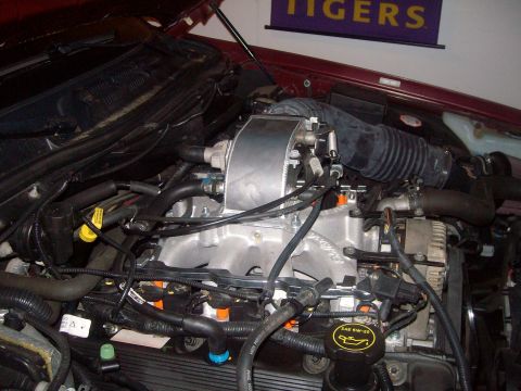 2004 Ford Crown Victoria - Close-up of an engine bay an aftermarket intake manifold and other engine components, with a SuperMotors logo visible.
