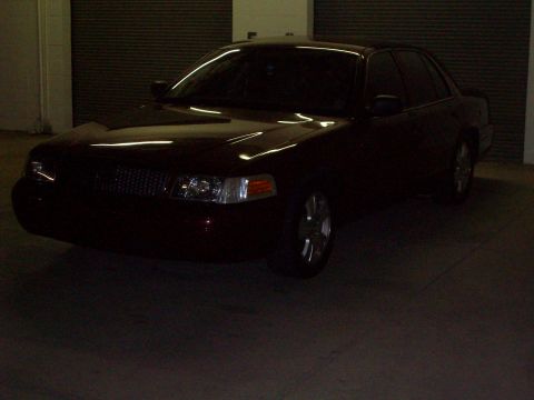 2004 Ford Crown Victoria - A dark red sedan is parked indoors, showing its front quarter with a visible grille and headlights.