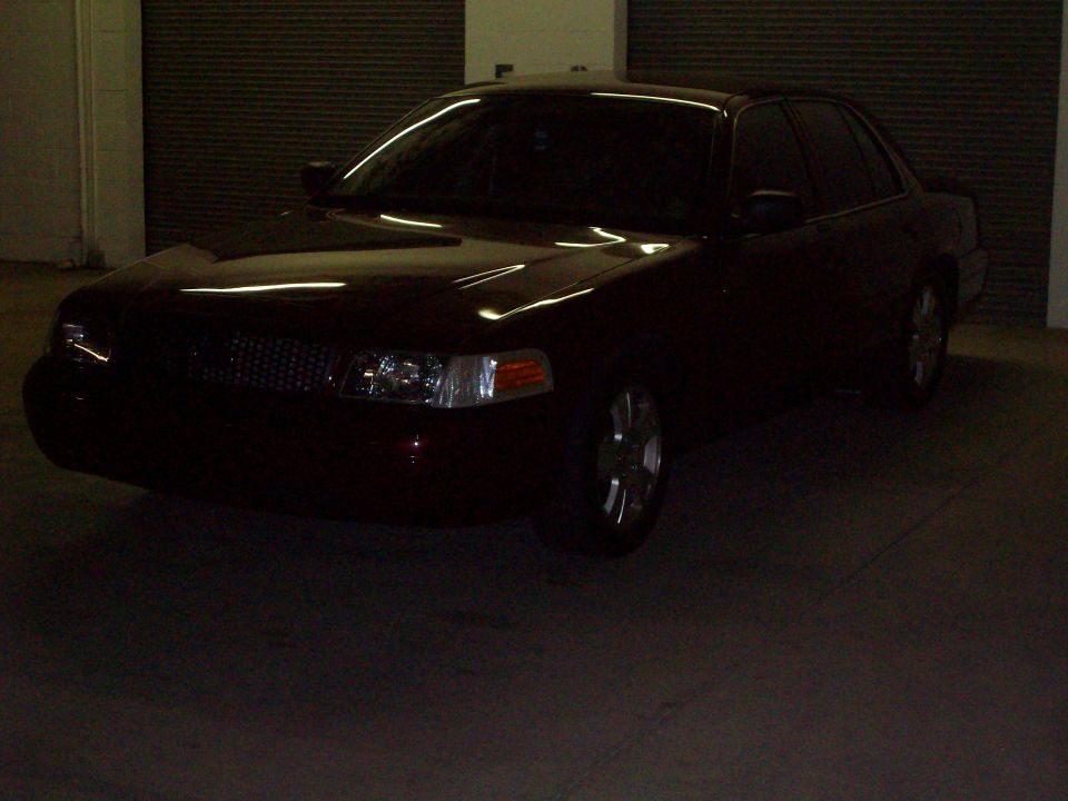 Dark red sedan, front quarter view, parked indoors. Visible grille and headlights