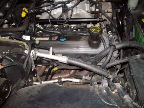 2004 Ford Crown Victoria - Close-up view of an engine bay, showing various hoses, wiring, and an oil cap indicating SAE 5W-30.