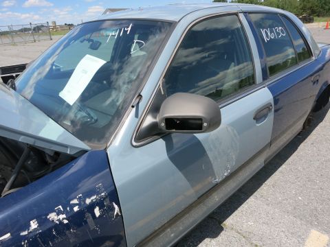 1991 Ford LTD Crown Victoria - A two-tone Ford Crown Victoria is shown from the front quarter angle with visible markings on the windshield and door.
